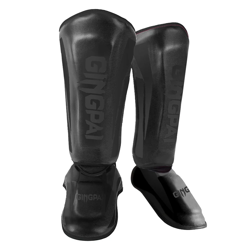 Black shin guards with "GINGPAI" logo, designed for protection in martial arts or sports, featuring a sturdy, curved structure.