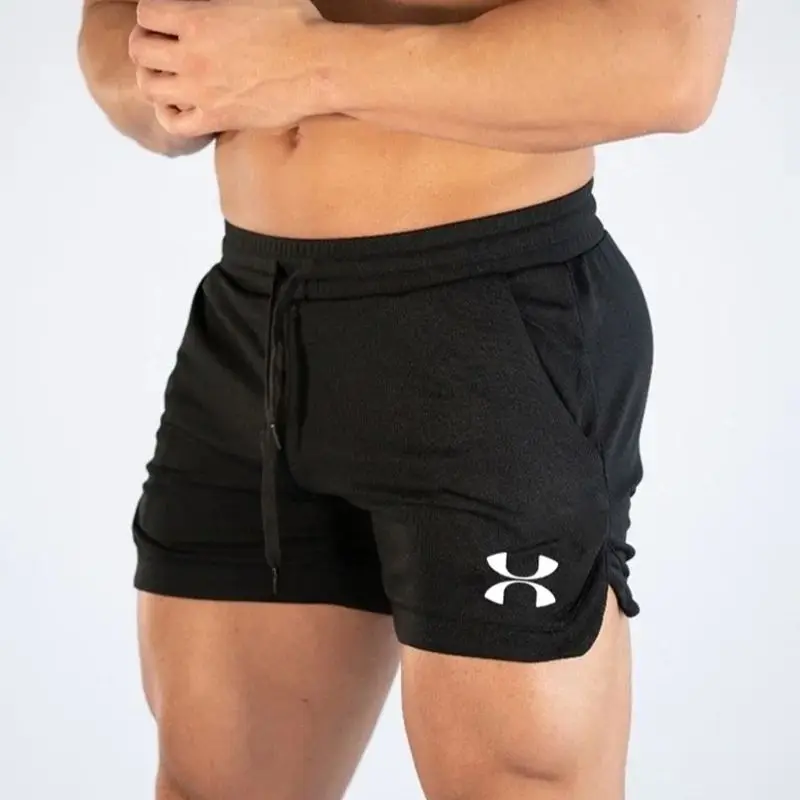 A muscular man wearing fitted black athletic shorts with the Under Armor logo, posing against a light background.